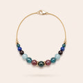 Wine and Roses handcrafted natural tourmaline, aquamarine and garnet bracelet with an 18K gold-coated sterling silver chain, photographed on a Pearled Ivory background.