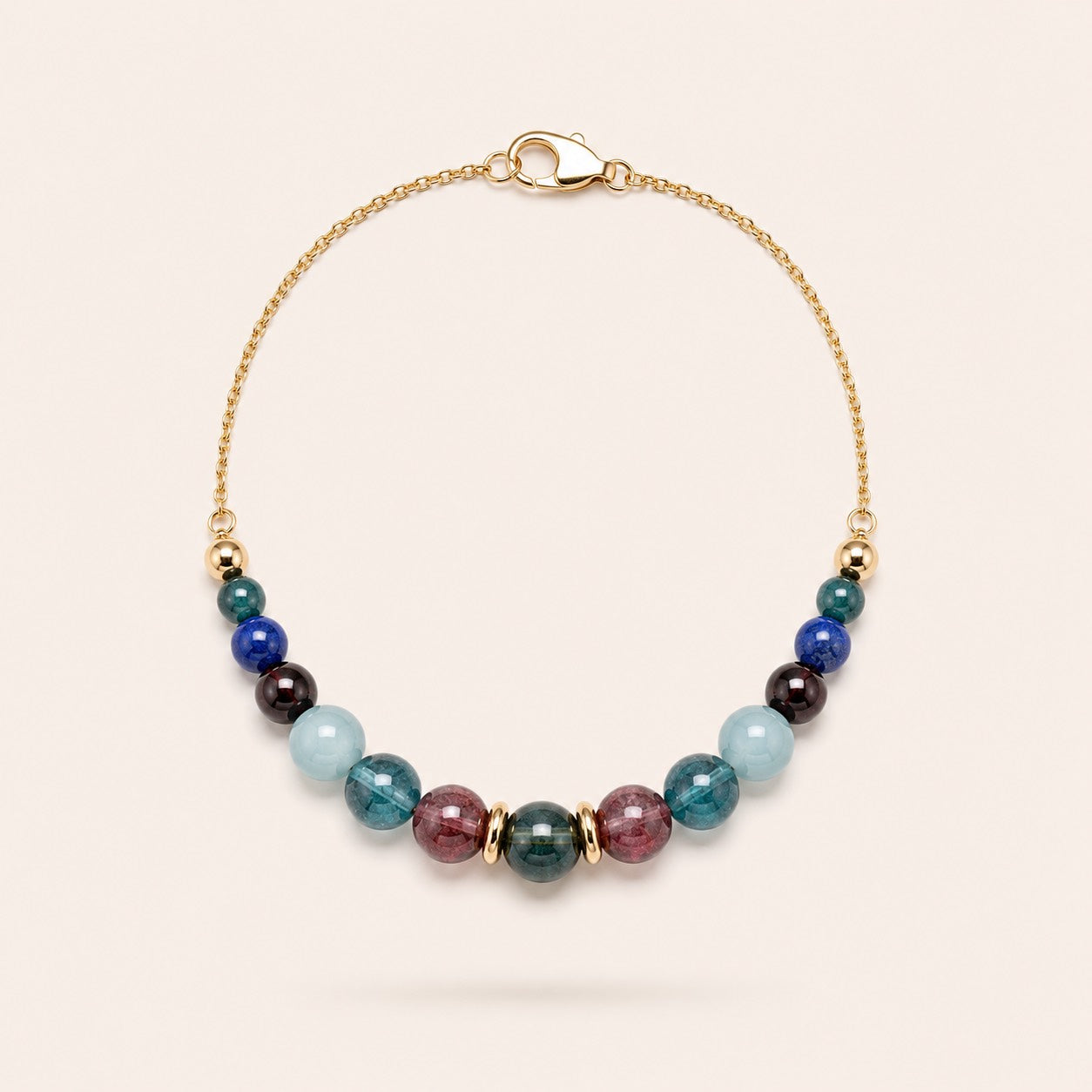 Wine and Roses handcrafted natural tourmaline, aquamarine and garnet bracelet with an 18K gold-coated sterling silver chain, photographed on a Pearled Ivory background.