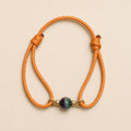 Petit Soleil orange cord bracelet with 7mm bi-color Watermelon Tourmaline and gold-plated details.