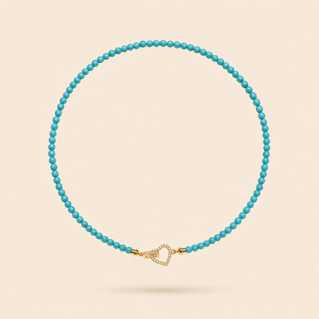 Little Crush natural turquoise bead necklace with a sparkling gold-tone heart clasp on an ivory background.